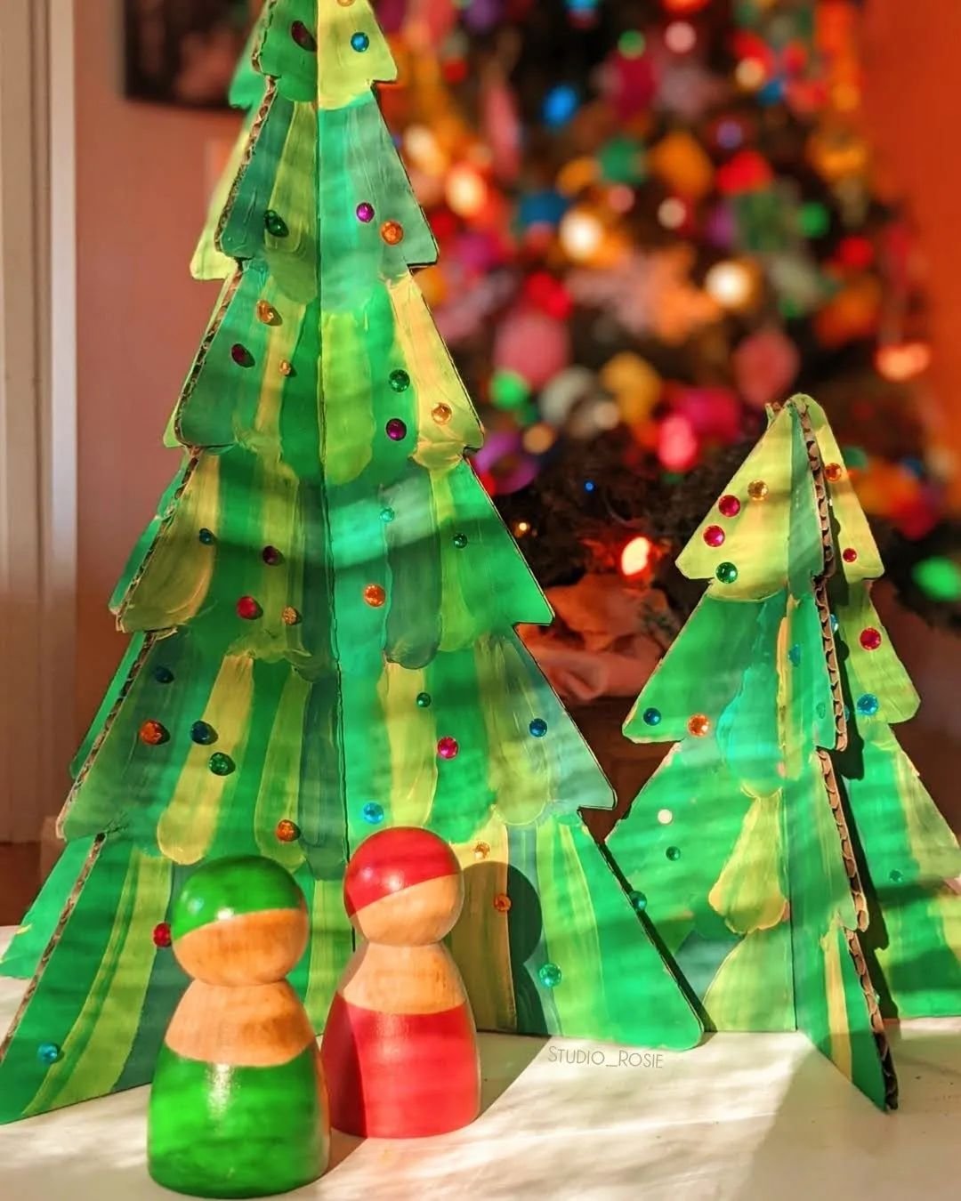 Festive scene with a cardboard Christmas tree and two wooden figures.
