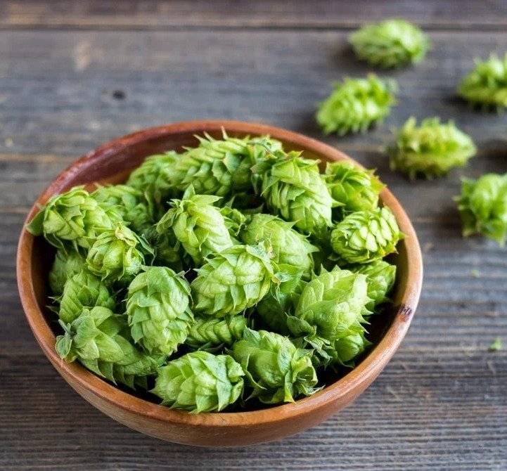 Hops in a bowl on a wooden table.


