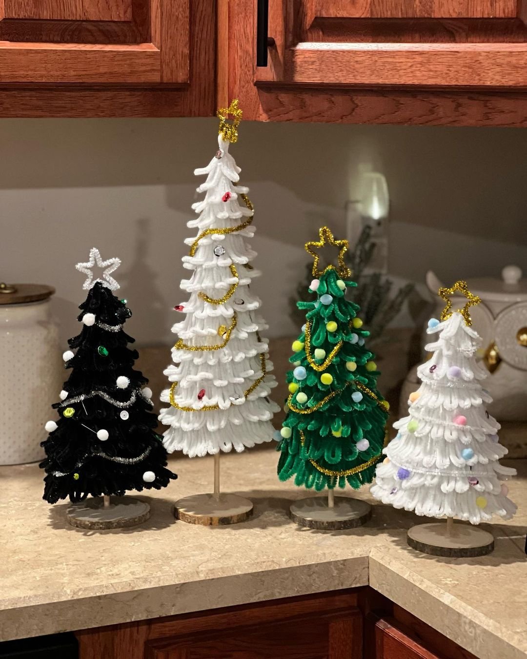 Three Christmas trees made of pipe cleaners on a kitchen counter.