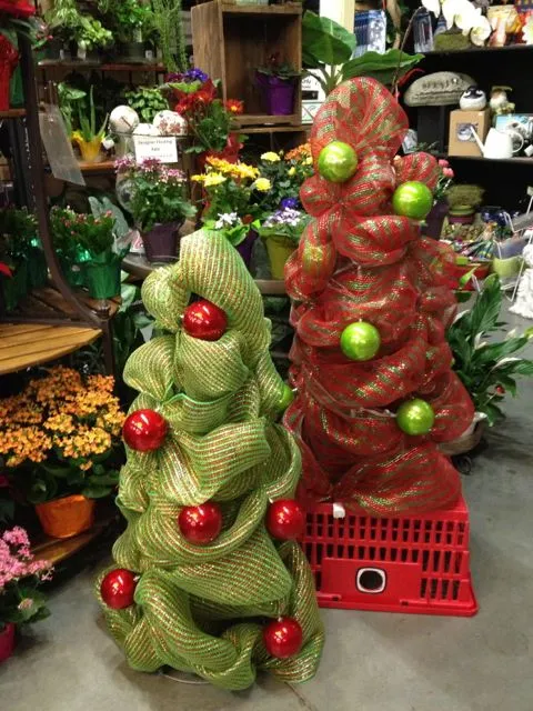 Two Tomato Cage Christmas Trees on display in a store, adorned with festive ornaments and lights.