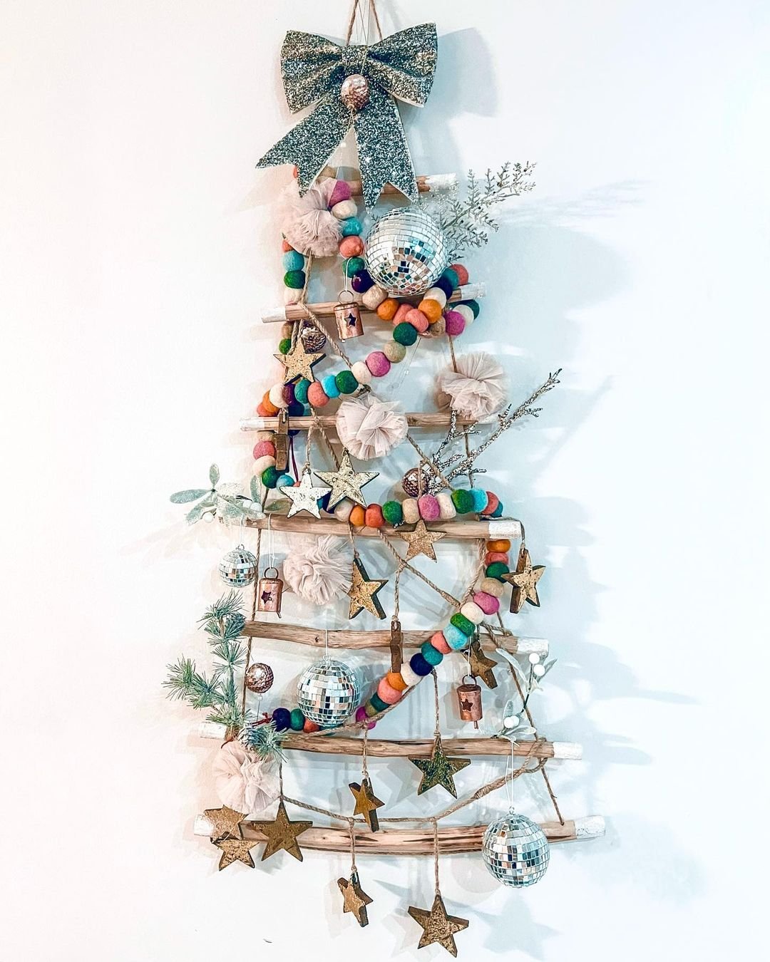 Wall-mounted wooden Christmas tree adorned with colorful ornaments.