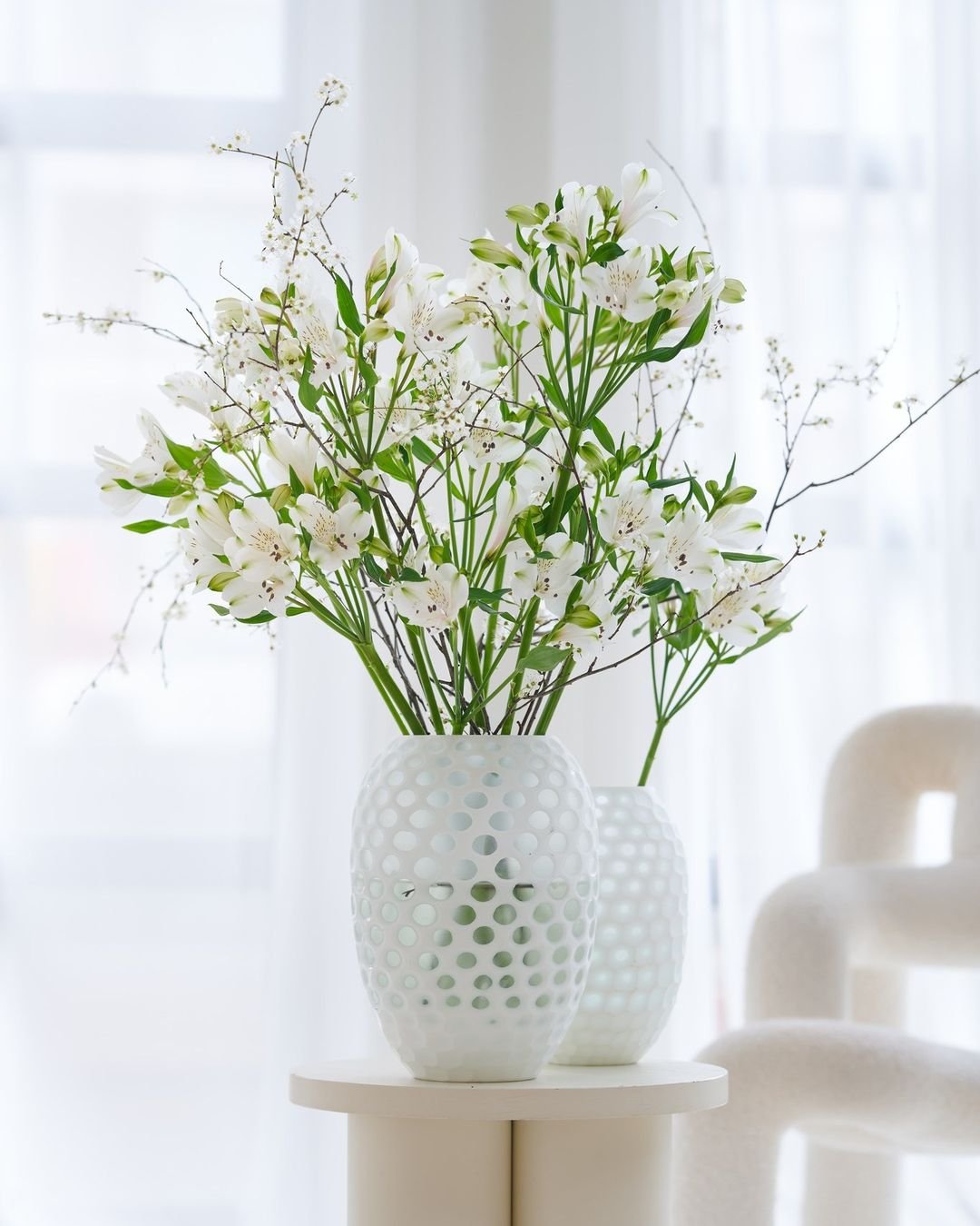 White Alstroemeria flowers in a white vase on a table.