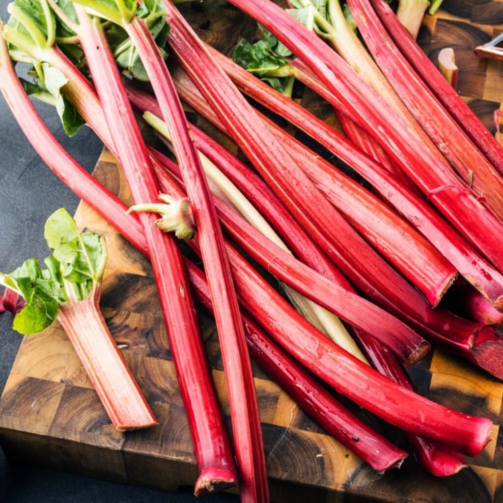 A pile of fresh rhubarb on a wooden cutting board.