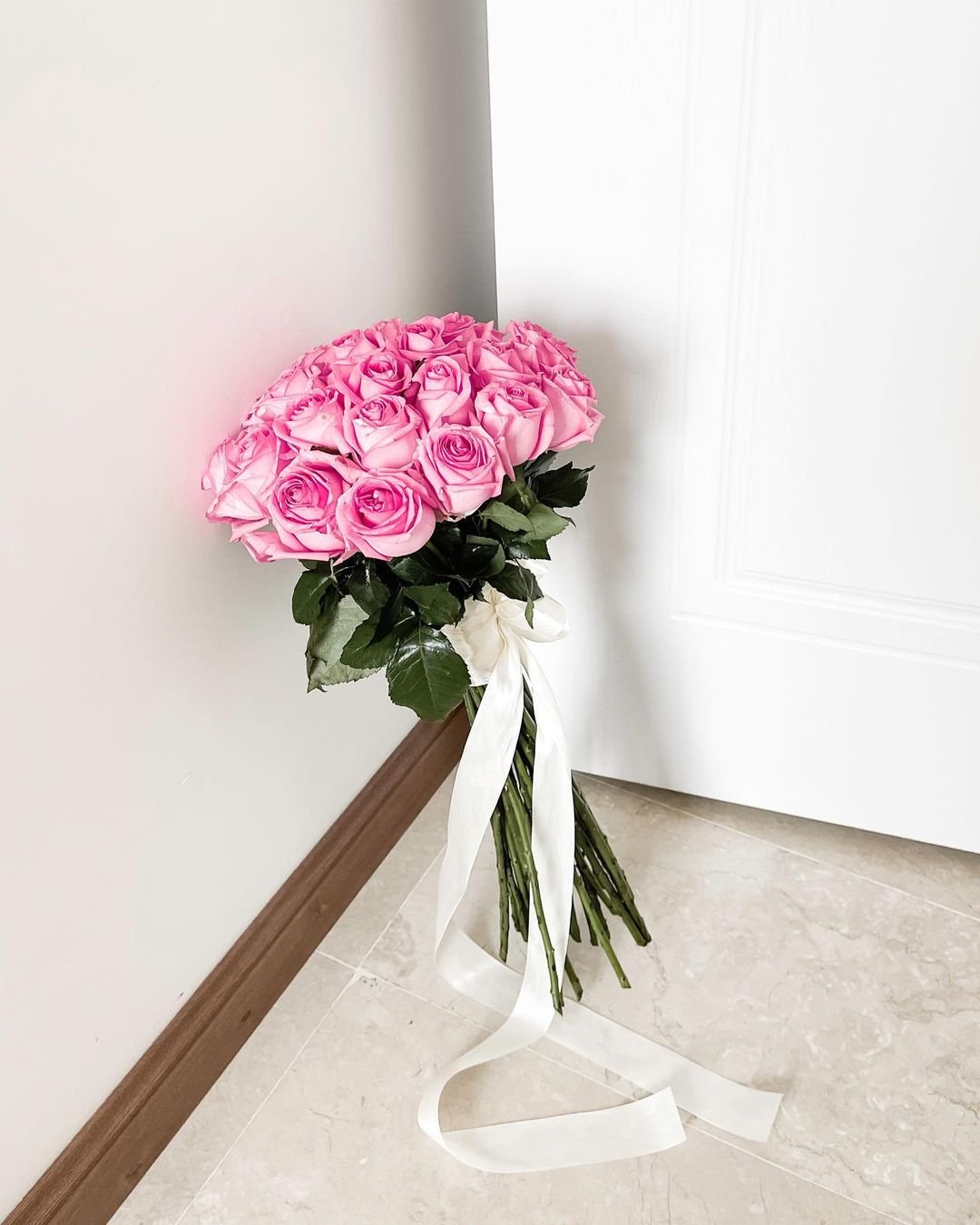  A lovely bouquet of pink roses hanging on a door.