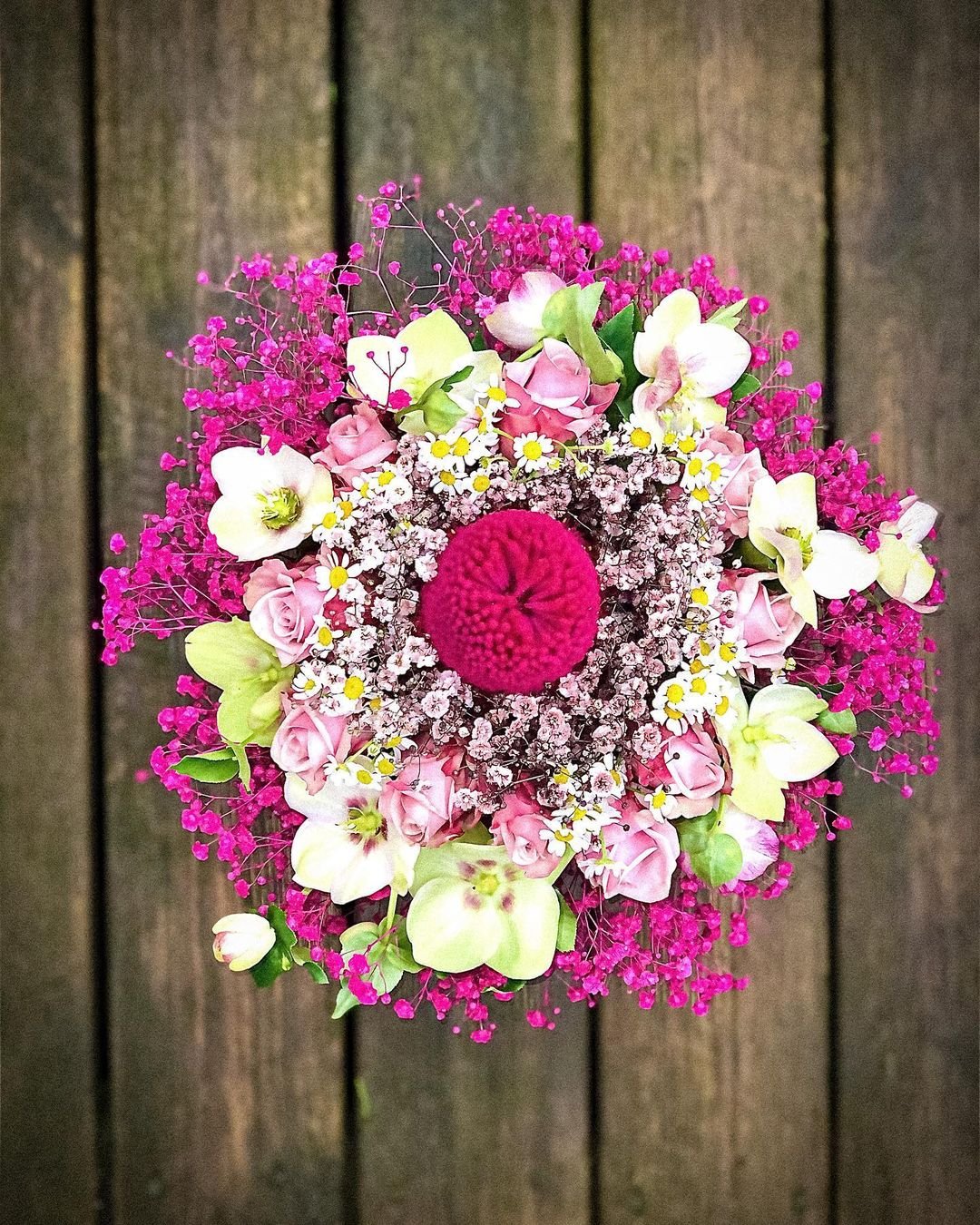  A Biedermeier bouquet of vibrant flowers elegantly arranged on a rustic wooden table, showcasing natural beauty and charm.