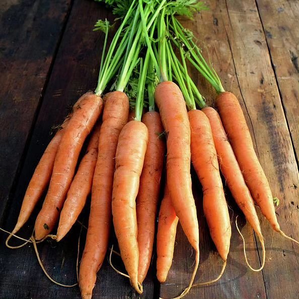 Organic carrots displayed on wooden surface.