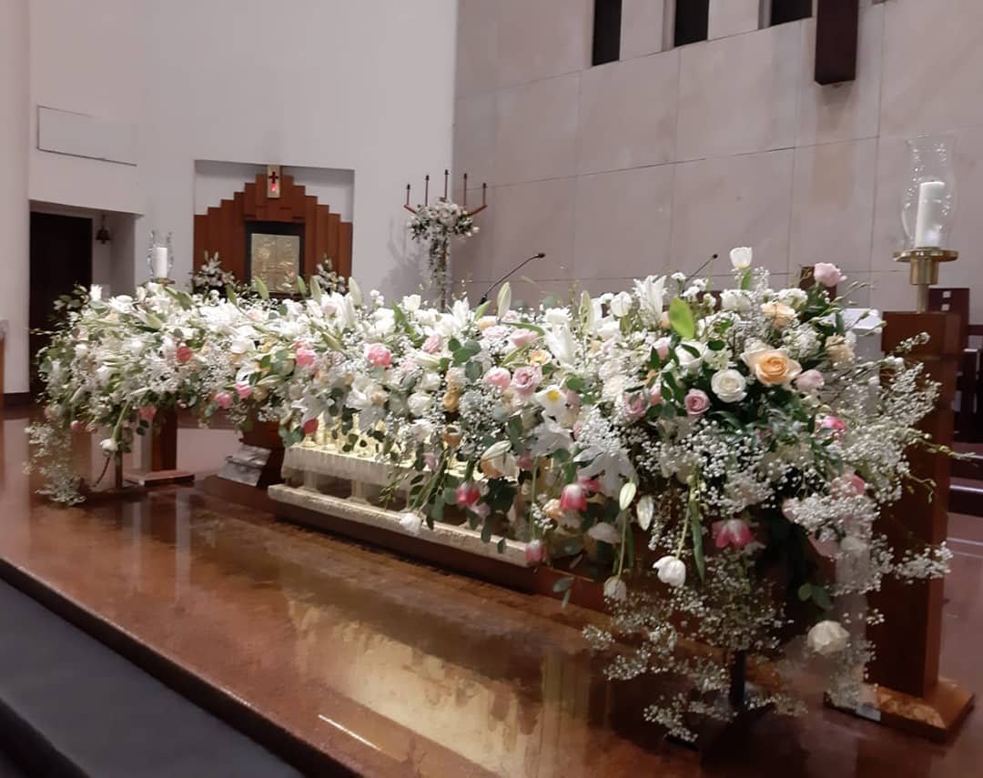 A large floral arrangement adorns a table in a church, enhancing the sacred atmosphere with vibrant colors and elegance.