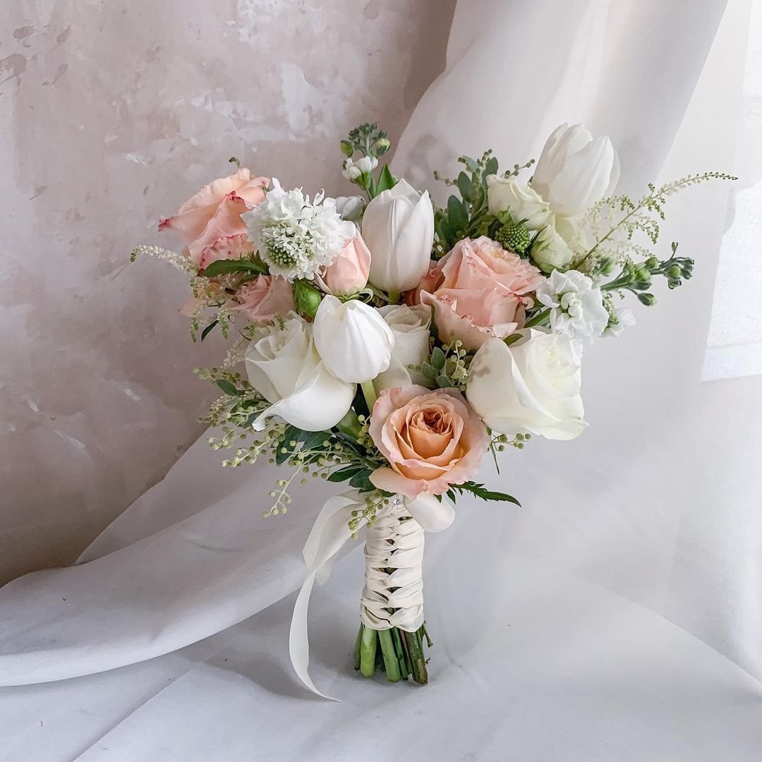 A nosegay bouquet featuring white and pink flowers elegantly arranged on a pristine white cloth.