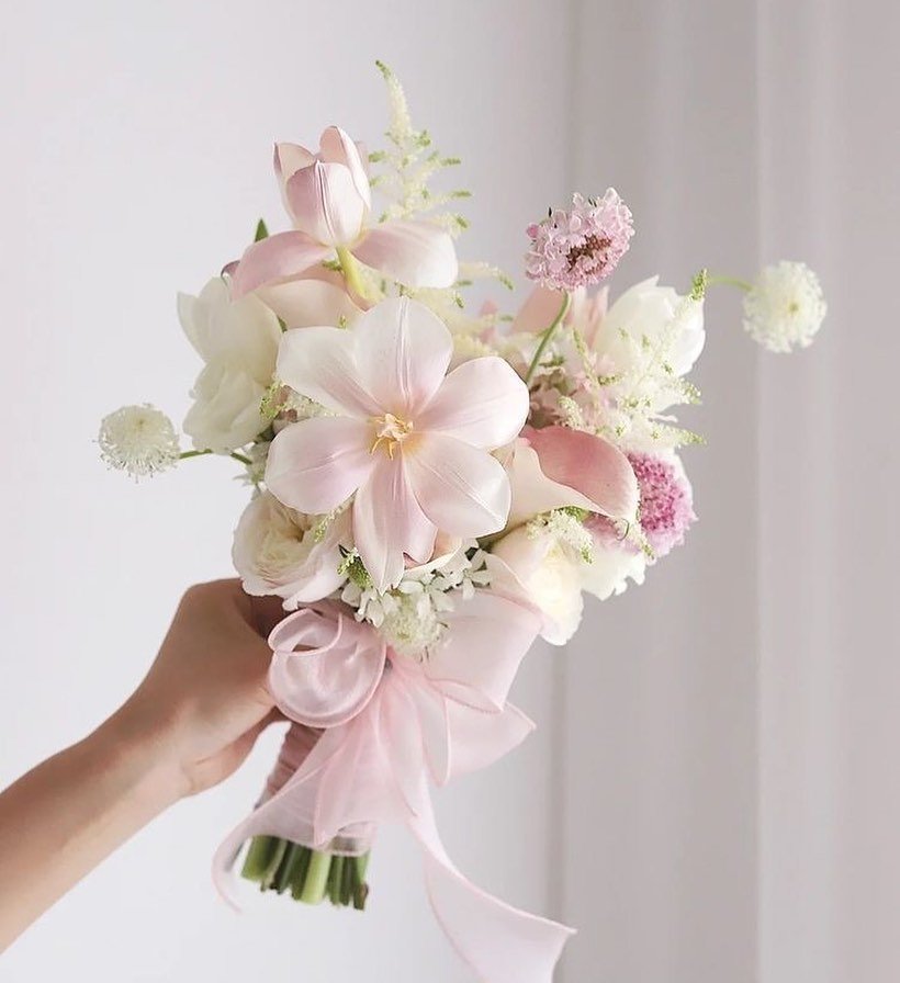  A hand gracefully holds a posy bouquet of vibrant pink flowers, showcasing their delicate beauty and charm.
