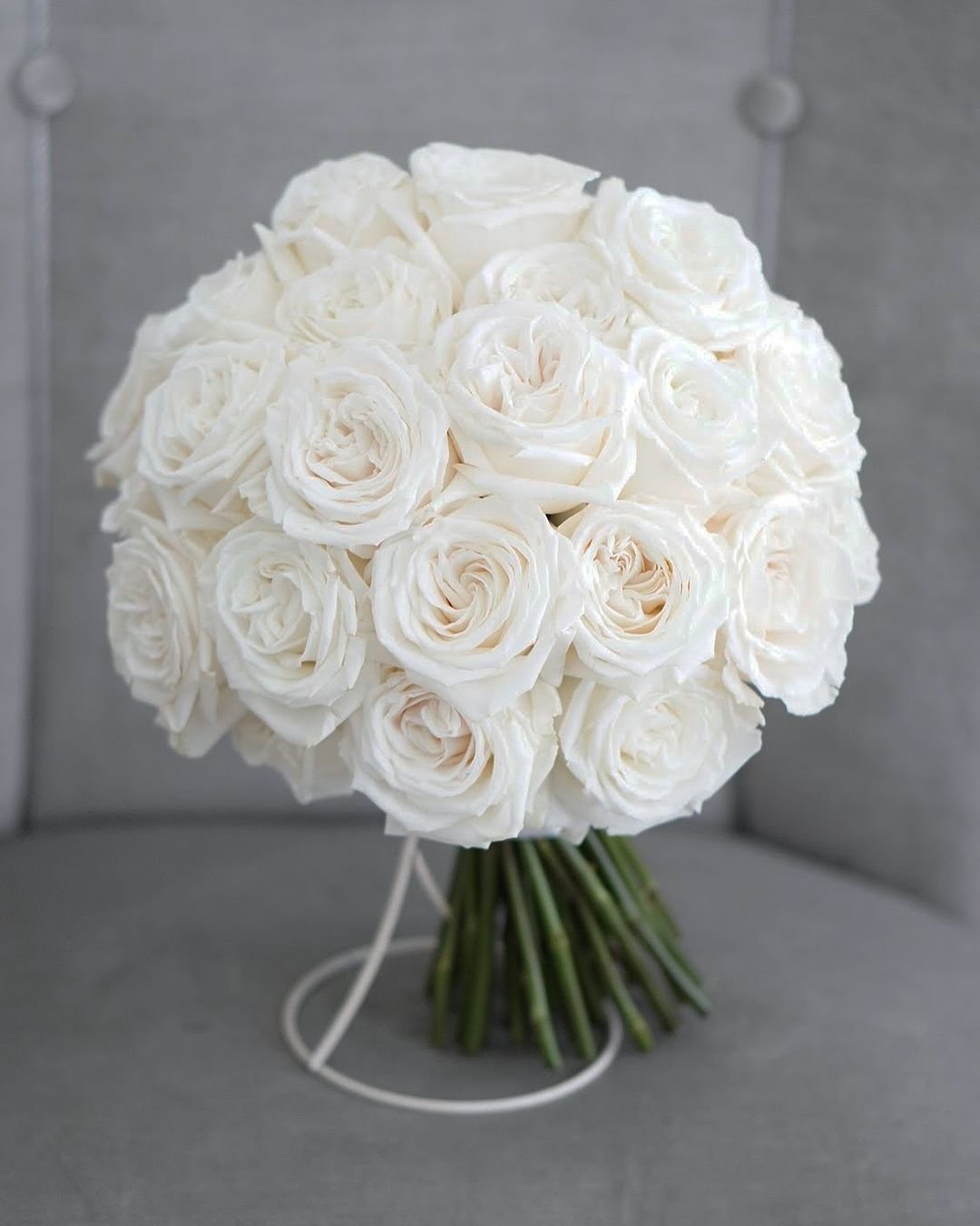 A bouquet of white roses elegantly arranged on a chair, showcasing their delicate petals and serene beauty.